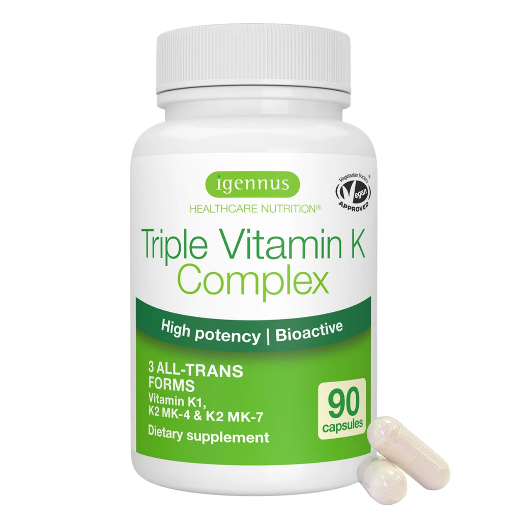 A white plastic bottle of Igennus Triple Vitamin K Complex dietary supplement with green and white labeling, shown on a white background with two beige capsules in front.