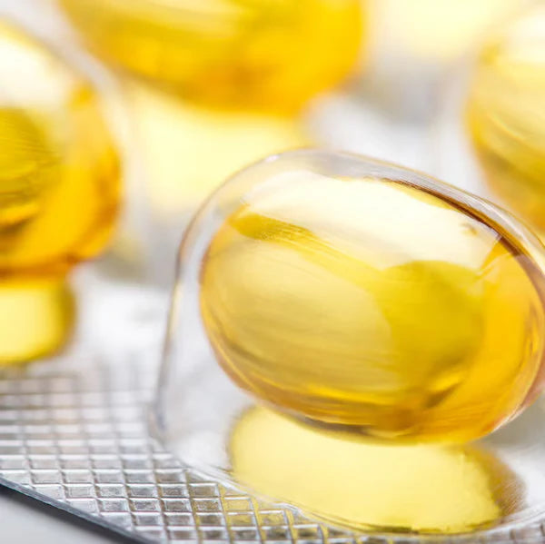 Close-up of yellow gelatin capsules on a metal rack.